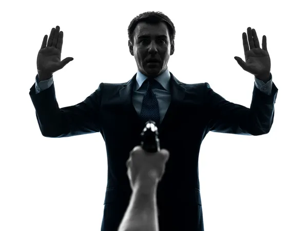 Business man arms raised with gun pointing at him silhouette — Stock Photo, Image
