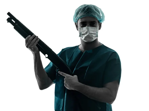 Doktor chirurg muž s obličejovou maskou držel brokovnici silueta — Stock fotografie