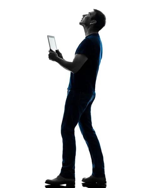 Человек держит цифровой планшет глядя на силуэт — стоковое фото