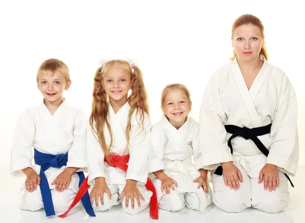 A boy with his sister and mother with her daughter sitting in a karate pose ritual — Stock Photo, Image