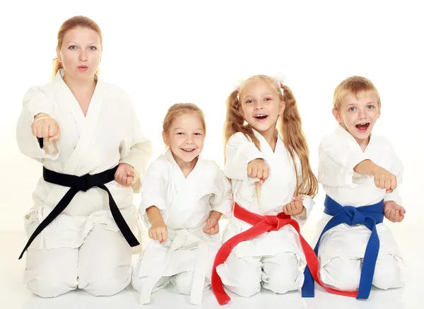 A boy sitting with his sister and mom with her daughter in a ritual pose karate and beat his fist — Stock Photo, Image