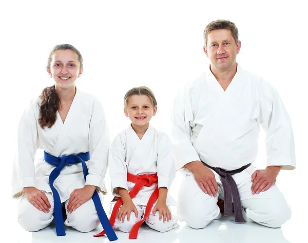 Papai com duas filhas sentadas em uma pose ritual Karate — Fotografia de Stock
