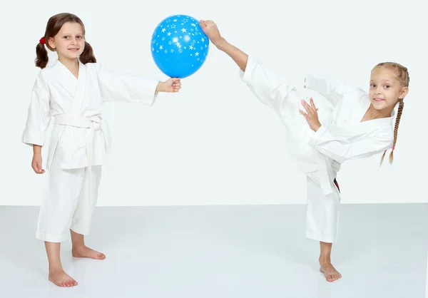 Две маленькие девочки с голубым мячом бьют ногами карате. — стоковое фото