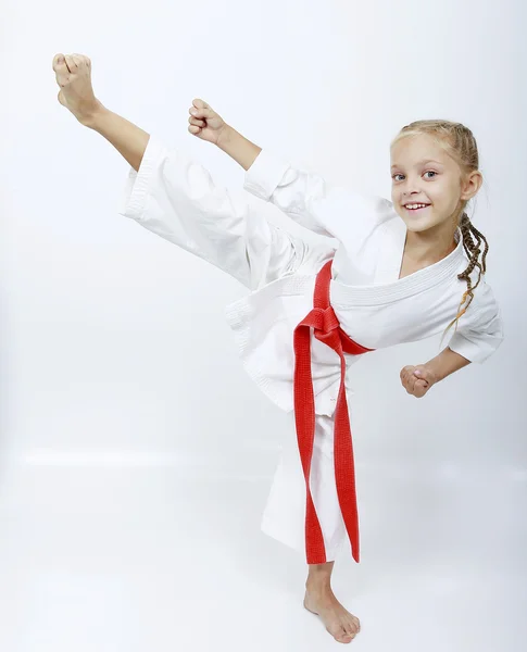 Mädchen im weißen Kimono mit rotem Gürtel schlägt Tritte — Stockfoto