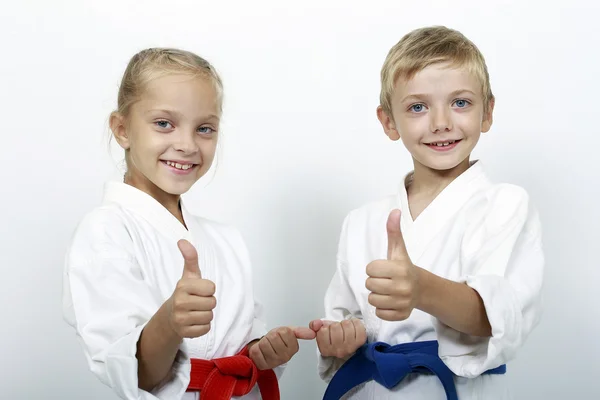 Children athletes with belts show a thumbs up — Stock Photo, Image