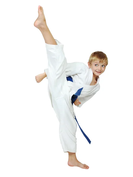 Em um fundo branco menino atleta em um quimono executa um pontapé perna circular isolado — Fotografia de Stock