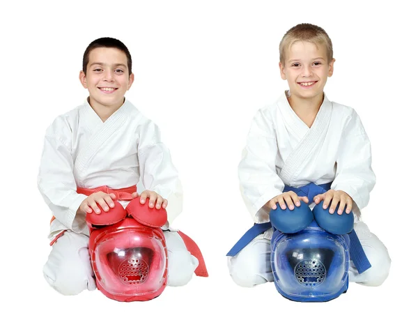 Athletes in kimono sitting in a ritual pose karate with helmets isolated — Stock Photo, Image