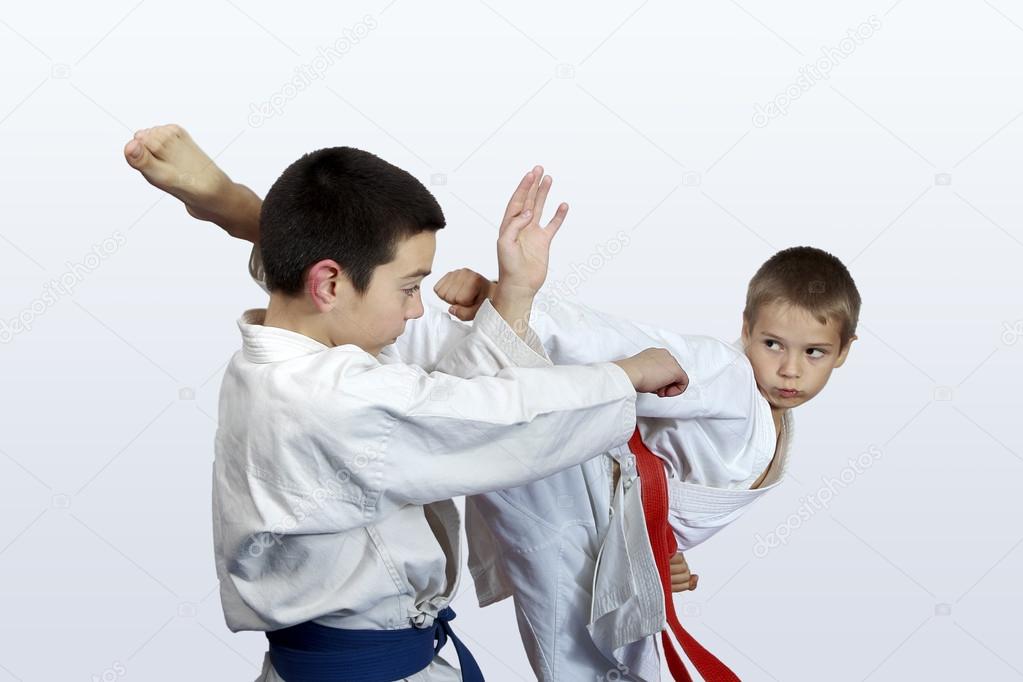 Two athletes with red and blue belt doing karate strikes