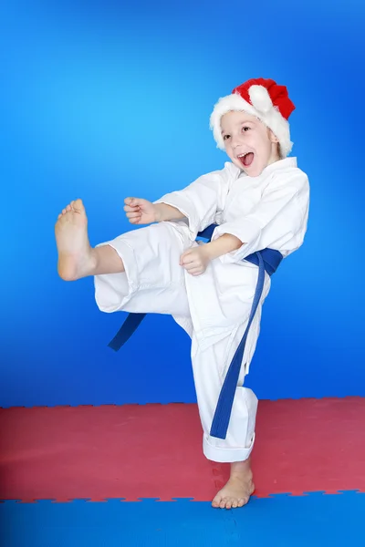 Girl beats a kick in the hat of Santa Claus — Stock Photo, Image