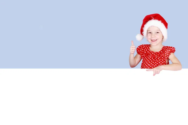 I en röd klänning och hatt jultomten visar en liten flicka ett finger på en skylt — Stockfoto