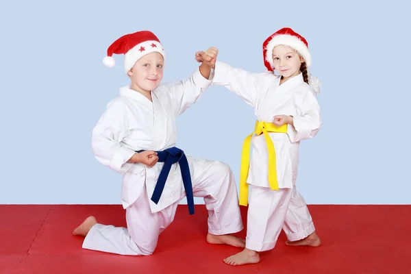 Menina e menino em chapéus Papai Noel fazendo engates e blocos — Fotografia de Stock