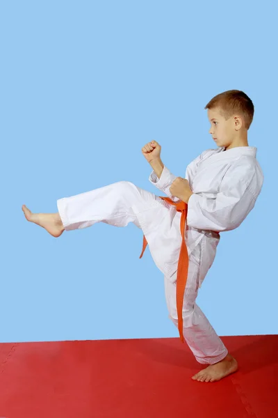 Menino com cinto laranja bater perna pontapé — Fotografia de Stock