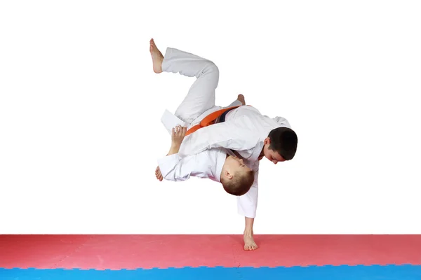 Athlete in kimono is throwing athlete with orange belt — Stock Photo, Image