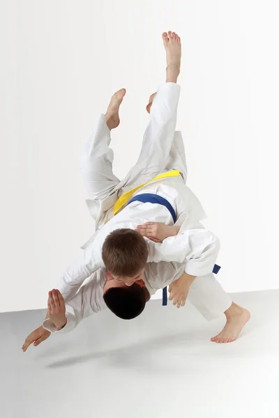 Two young athletes in kimono are performing throws