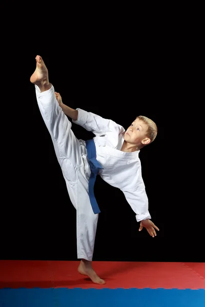 Com um cinto azul um atleta fazendo chute mawashi-geri em um fundo preto — Fotografia de Stock