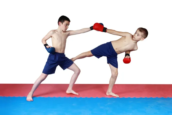 Two athletes are training in shorts kick low kick on the mat — Stock Photo, Image