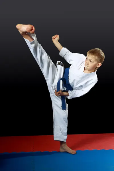En blanco karategi atleta haciendo patada yoko-geri pie derecho — Foto de Stock