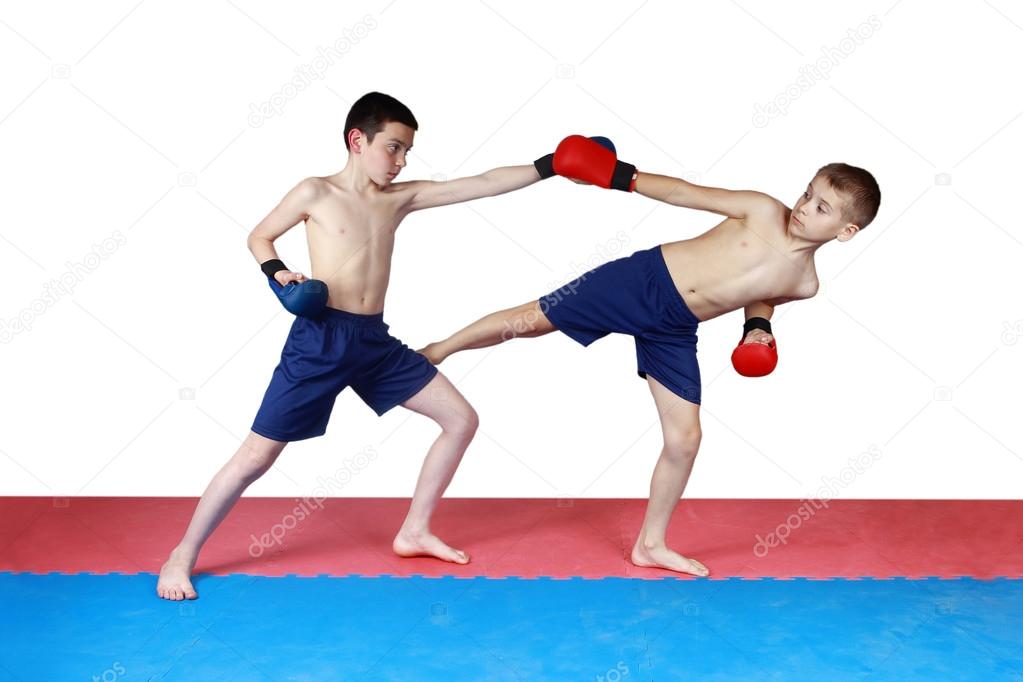 Two athletes are training in shorts kick low kick on the mat