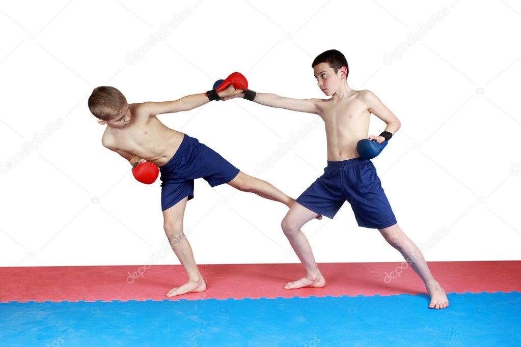 Boy in shorts and red lining hit low kick other