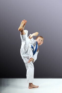 gri bir arka plan üzerinde küçük çocuk mawashi geri atıyor