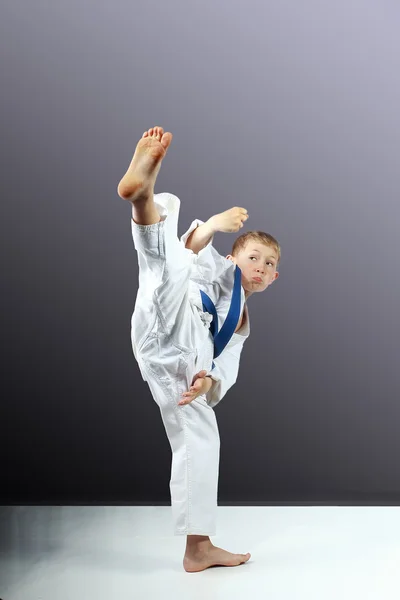 On a gray background little boy is beating mawashi geri — Stock Photo, Image