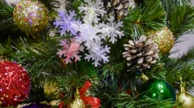 Yeşil bir Noel ağacında farklı Noel oyuncakları ve açık bir arka planda hediyeler.
