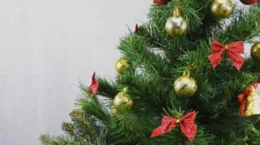 Küçük bir Noel ağacı ve bir Noel balosu, dönen yeşil bir Noel ağacının arka planında duran bir hediye standı.