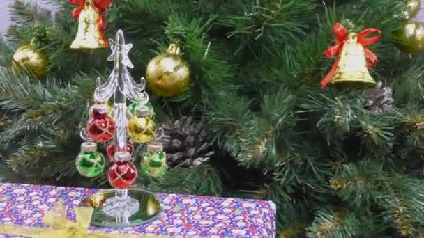 一棵小圣诞树站在礼物上 背靠着一棵旋转的装饰过的绿色圣诞树 — 图库视频影像