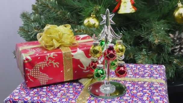 在一棵旋转的圣诞树的背景下 一棵小圣诞树立在礼物上 — 图库视频影像