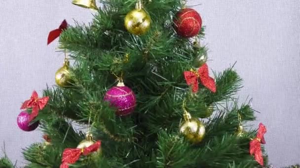 一棵小圣诞树和一根燃着的蜡烛倒立在一棵旋转着的圣诞树后面的礼物上 — 图库视频影像