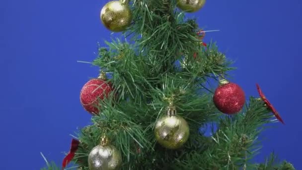 Een Grote Groen Versierde Kerstboom Draait Een Blauwe Achtergrond — Stockvideo