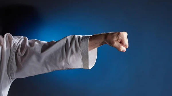 Sportler Karategi Führt Einen Schlagarm Auf Blauem Hintergrund Vor — Stockfoto