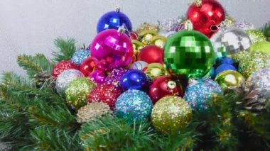 Noel ağacı dalları ve konileri arasında hareket eden bir sürü renkli Noel topuyla yakın plan.