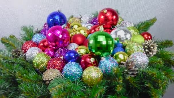 在圣诞树树枝和圆锥之间的许多彩色圣诞球的特写 — 图库视频影像