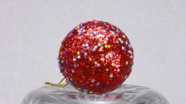 Kırmızı parlak Noel ağacı oyuncağı ışık arka planında döner