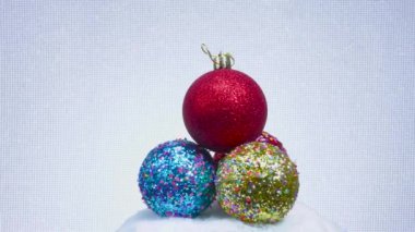 Dört renkli Noel ağacı topları beyaz bir yüzey üzerinde yatar ve döner.