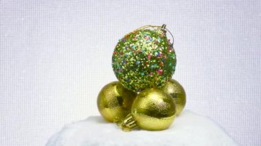 Yıldızlarla süslenmiş bir top üç sarı top üzerinde yatar ve beyaz bir yüzey üzerinde döner.