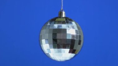 Gümüş bir Noel balosu mavi bir arka planda dönüyor.