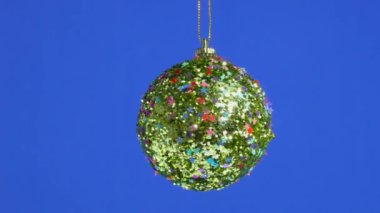 Yıldızlarla süslenmiş altın bir top mavi bir arka planda dönüyor.