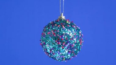 Mavi bir arka planda, yıldızlarla süslenmiş mavi bir top dönüyor.