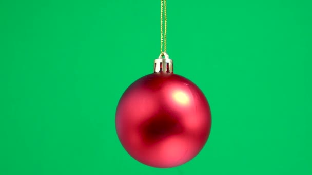 Rode Matte Kerst Speelgoed Bal Draait Een Groene Effen Achtergrond — Stockvideo