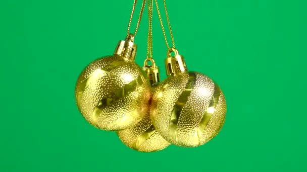 Drie Gouden Kerstballen Draaien Een Groene Effen Achtergrond — Stockvideo