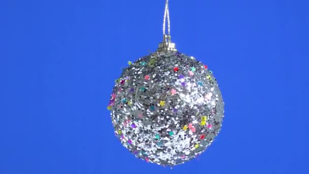 一只饰有星星的银色圣诞玩具球在蓝色的平原背景上旋转着 — 图库视频影像