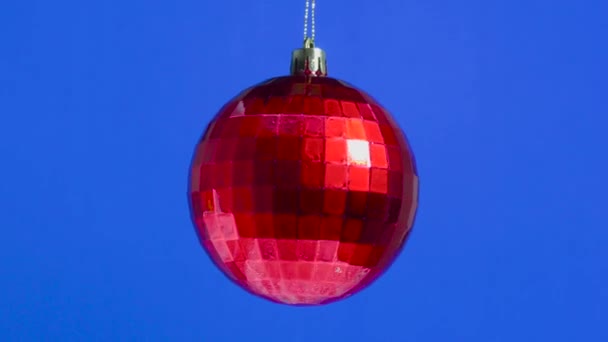 一只装在盒子里的红色圣诞玩具球在蓝色的普通背景上旋转着 — 图库视频影像