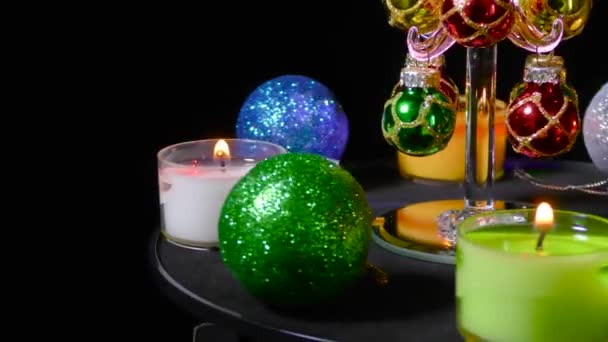 小さなクリスマスツリーは 多色のクリスマス燃焼キャンドルやボールに囲まれて回転します — ストック動画
