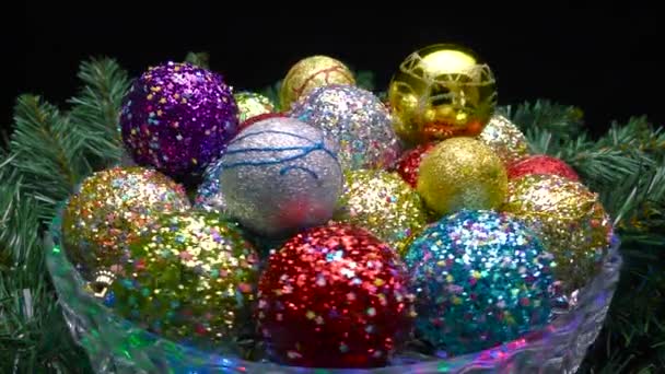 ガラスの花瓶には クリスマスツリーの枝に模様のあるカラフルなボールが回転します — ストック動画