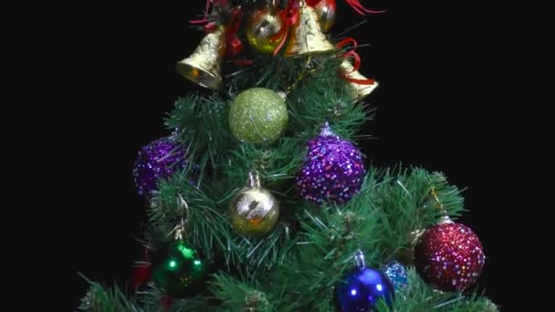 火のろうそくの後ろに動くクリスマスは おもちゃと黒の背景を持つ白い毛布の上にクリスマスツリーを回転させます — ストック動画