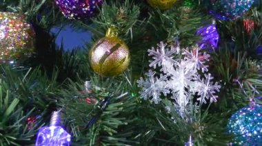 Noel, mavi arka planda toplar ve kar taneleriyle süslenmiş büyük bir Noel ağacı.