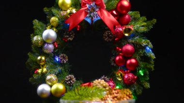 Noel çelenginin arka planında hareketli bir Noel vazosu koni ve Noel ağacı dalları dönüyor.