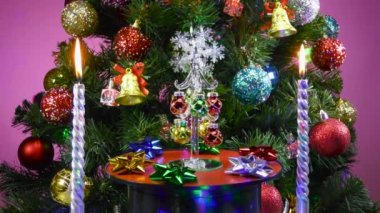 Büyük bir Noel ağacının önünde pembe bir arka planda küçük bir Noel ağacı dönüyor.